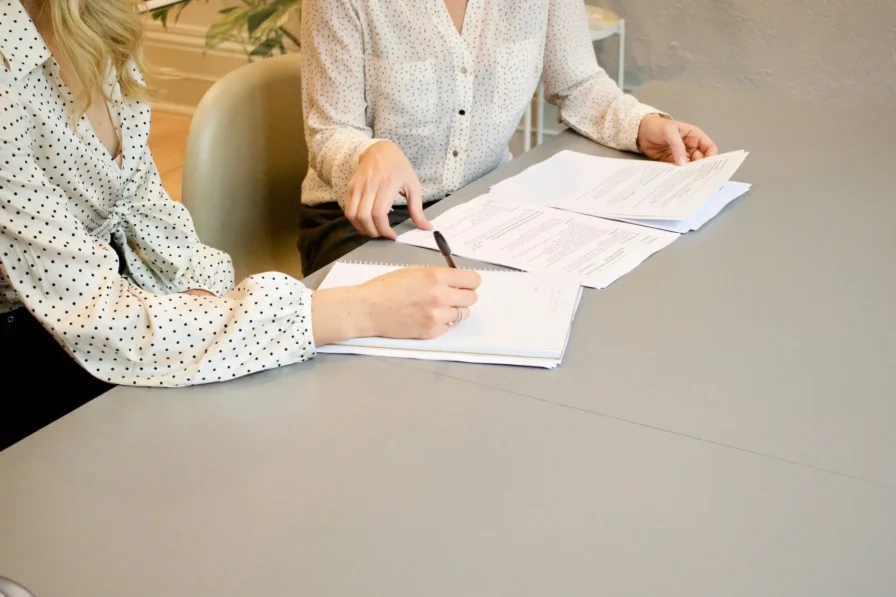 two women filling out paperwork at a desk